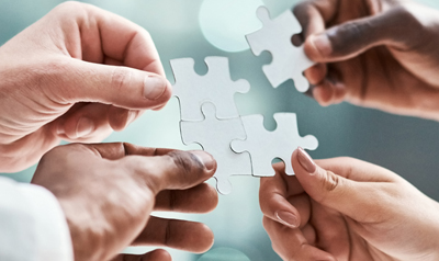 Vier Hände fügen ein modulares Puzzle zusammen